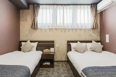 a bedroom with two beds and a window at Playsis Asakusa in Tokyo