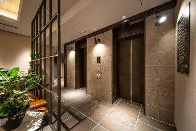 a corridor of a building with brown tile walls at HOTEL AMANEK Kamata-Eki Mae in Tokyo