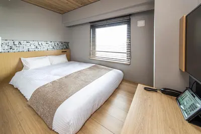 a bedroom with a large white bed and a television at HOTEL AMANEK Kamata-Eki Mae in Tokyo