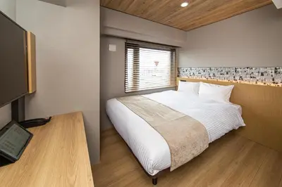 a bedroom with a large white bed and a window at HOTEL AMANEK Kamata-Eki Mae in Tokyo