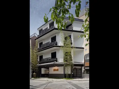 a white building with black balconies and a tree at The Edo Sakura in Tokyo