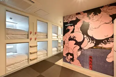 a room with bunk beds and a wall with a painting at Hotel Tomariya Ueno in Tokyo