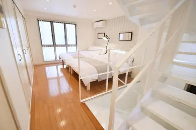 a white bedroom with a bed and a staircase at TERRACE HOUSE Shibuya Maruyamacho in Tokyo