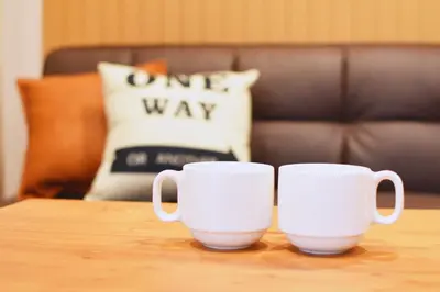 two white coffee mugs sitting on a wooden table at TERRACE HOUSE Shibuya Maruyamacho in Tokyo