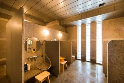 a bathroom with two stalls with a mirror and a sink at Super Hotel Premier Tokyo Station Yaesu-Chuoguchi in Tokyo