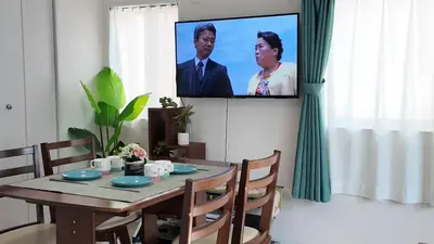 a living room with a table and a tv on a wall at First sight hut house in Tokyo