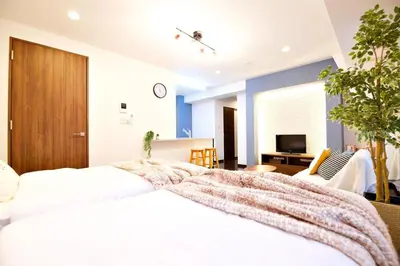 a bedroom with a large white bed and a living room at Kanbe Building 301 in Tokyo