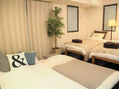 a room with three beds and a potted plant at Kanbe Building 301 in Tokyo