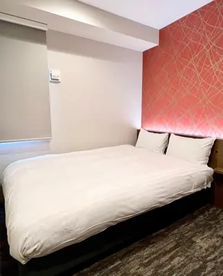 a bedroom with a white bed with a red wall at KIN HOTEL in Tokyo