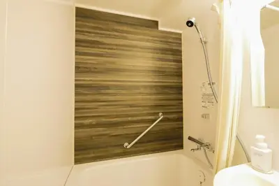 a bathroom with a wooden wall behind a tub at KIN HOTEL in Tokyo