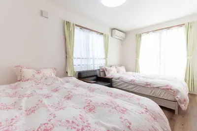 two beds in a bedroom with pink and white sheets at Mori House In \u897f\u65e5\u66ae\u91ccI in Tokyo