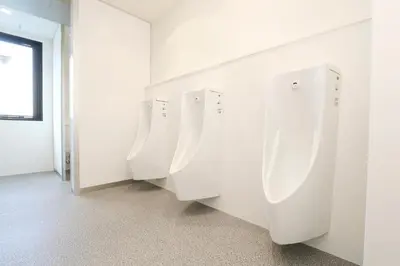 a row of white urinals in a bathroom at Capsule Room Lightning Hotel Asakusa in Tokyo
