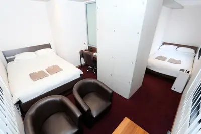 a small room with two beds and a chair at Capsule Room Lightning Hotel Asakusa in Tokyo