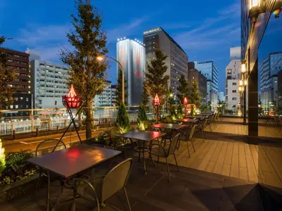 a row of tables and chairs on a balcony with a city skyline at APA Hotel Yamanote Otsuka Ekimae Tower in Tokyo