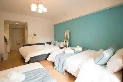 a room with three beds and a blue wall at Roppongi Azabu Gorgeous Sea House in Tokyo