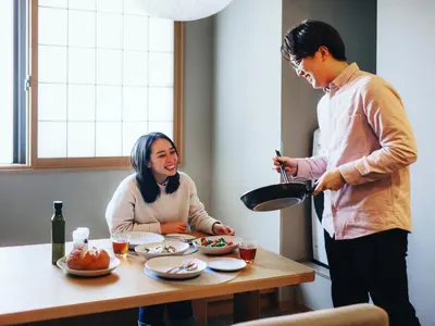 a man holding a pan and a woman sitting at a table at MIMARU Tokyo Ginza East in Tokyo