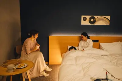 two women sitting on a bed next to a woman laying in bed at MIMARU Tokyo Ginza East in Tokyo