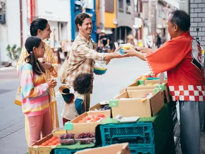a group of people standing around a fruit stand on a street at MIMARU Tokyo Ueno Okachimachi in Tokyo