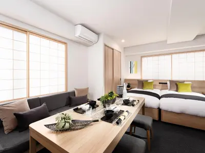 a living room with a bed and a wooden table at MIMARU Tokyo Ueno Okachimachi in Tokyo