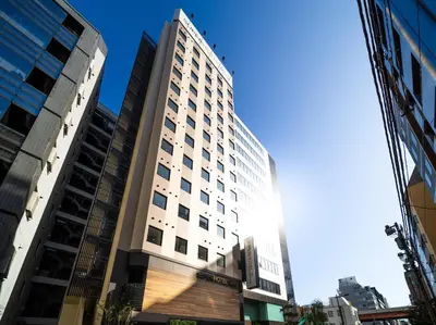 a tall white building with the sun shining on it at Super Hotel Premier Akihabara in Tokyo