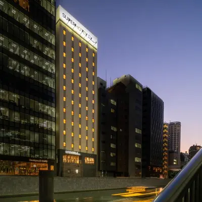 a tall building with lights on in a city at Super Hotel Premier Akihabara in Tokyo