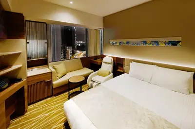 a hotel room with a bed and a chair at remm plus Ginza in Tokyo