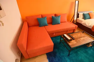 an orange couch with blue pillows in a room at Roppongi Azabu Sunshine Resort House in Tokyo