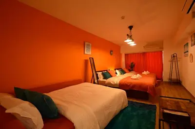 two beds in a room with orange walls at Roppongi Azabu Sunshine Resort House in Tokyo