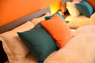 a bed with several pillows on it with an orange wall at Roppongi Azabu Sunshine Resort House in Tokyo