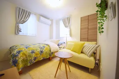 a bedroom with a bed and a yellow couch at Three Tokyo 102 in Tokyo