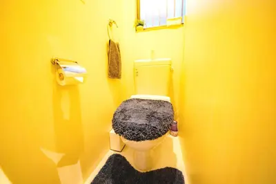 a yellow bathroom with a toilet with a blanket on it at SMILE STAY Shinnakano in Tokyo