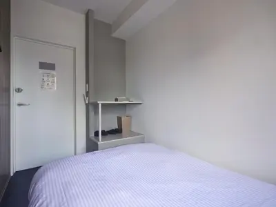 a small bedroom with a bed and a door at &AND HOSTEL MINAMISENJU in Tokyo