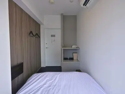 a small room with a bed and a closet at &AND HOSTEL MINAMISENJU in Tokyo