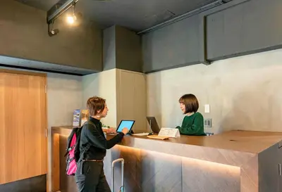 two people standing at a desk with their laptops at &AND HOSTEL MINAMISENJU in Tokyo