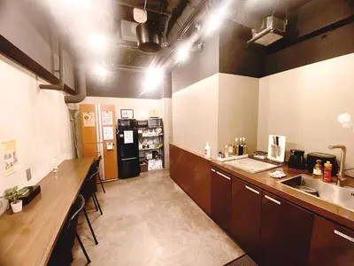 a large kitchen with a counter and a refrigerator at &AND HOSTEL MINAMISENJU in Tokyo