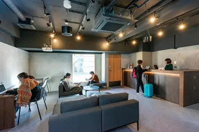 a group of people sitting in a waiting room at &AND HOSTEL MINAMISENJU in Tokyo