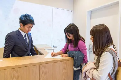 a man and a woman signing a piece of paper at Sakura Cross Hotel Tokyo Kayabacho in Tokyo