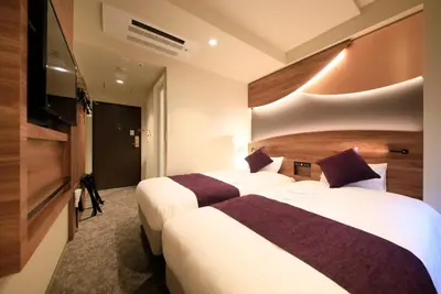 a hotel room with two beds and a flat screen tv at Quintessa Hotel Tokyo Ginza in Tokyo