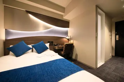 a bedroom with a large bed with blue pillows at Quintessa Hotel Tokyo Ginza in Tokyo