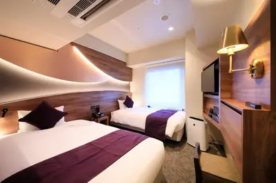 a hotel room with two beds and a television at Quintessa Hotel Tokyo Ginza in Tokyo