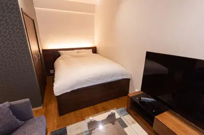 a small bedroom with a bed and a flat screen tv at NIYS apartments 03 type in Tokyo