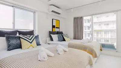 two beds in a room with a window at Hotel Apartment Ueno Inaricho Sta in Tokyo