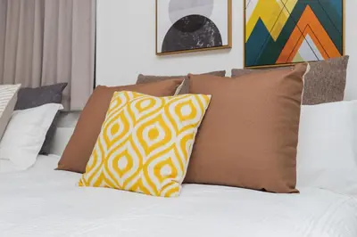 a bed with brown and white pillows on it at Hotel Apartment Ueno Inaricho Sta in Tokyo