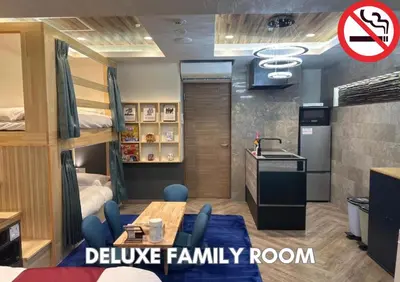 a room with bunk beds with a table and blue chairs at Hotel Pasela Living Shinjuku in Tokyo