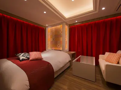 a bedroom with red curtains and a bed and a couch at Hotel Crest Hirai (Adult Only) in Tokyo