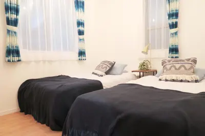 two beds in a room with blue and white curtains at Etranger Kaname Cho in Tokyo