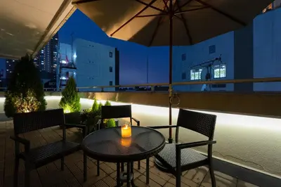 a table and chairs on a balcony with an umbrella at Hotel Tokyo Trip Ueno Nishi Nippori in Tokyo