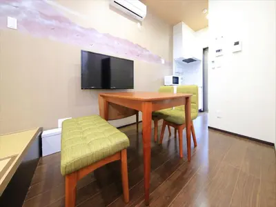 a room with a table and chairs and a flat screen tv at COTO Tokyo Nakano in Tokyo