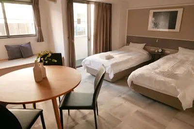 a hotel room with two beds and a table at Tokyo Sakurako Hatchobori in Tokyo