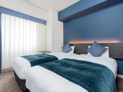 two beds in a hotel room with blue walls at Villa Fontaine Tokyo Hamamatsucho in Tokyo